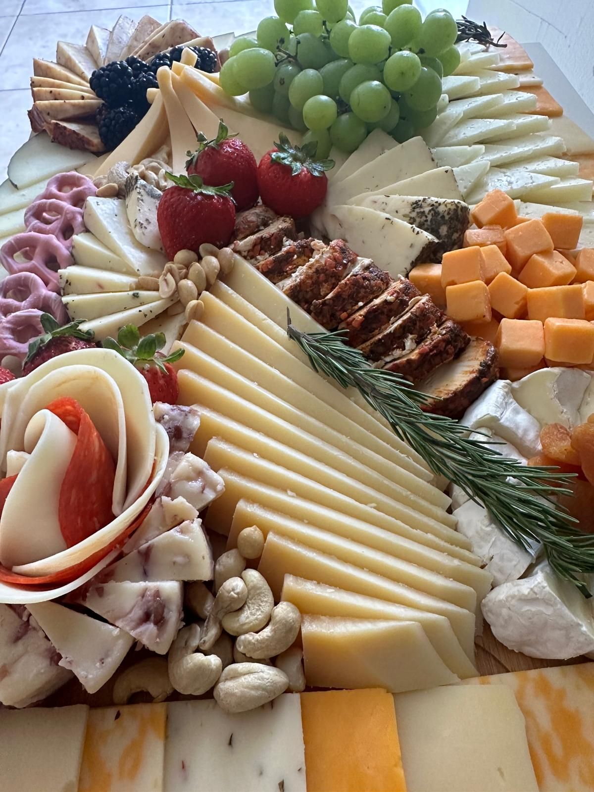 Board of cheeses, cured meats, grapes and strawberries