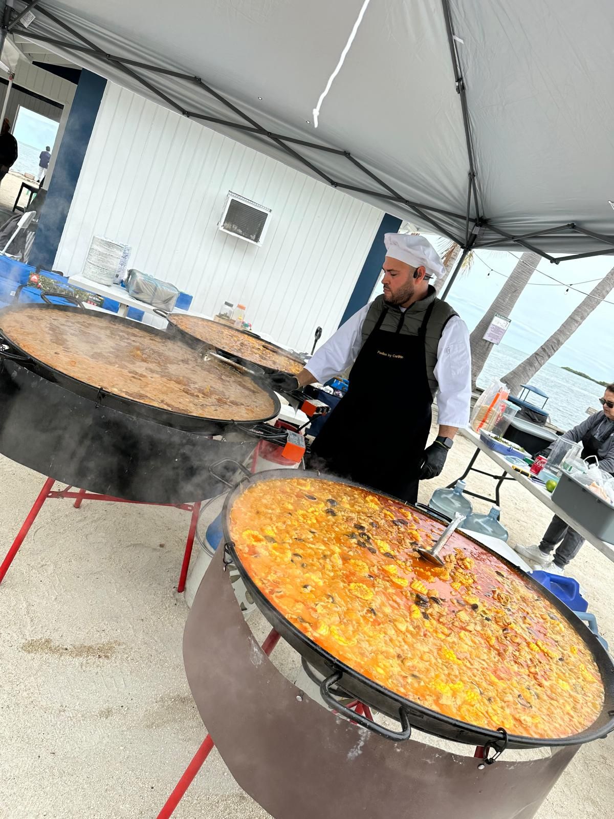 Chef stirring two giant paella pans
