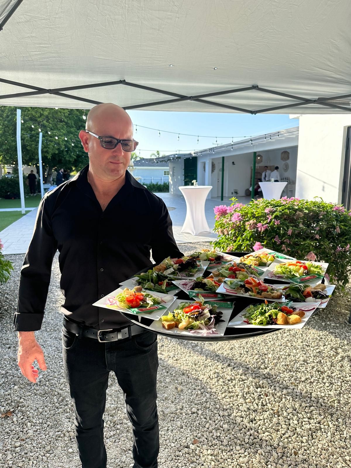 Server with a tray of appetizers in a garden